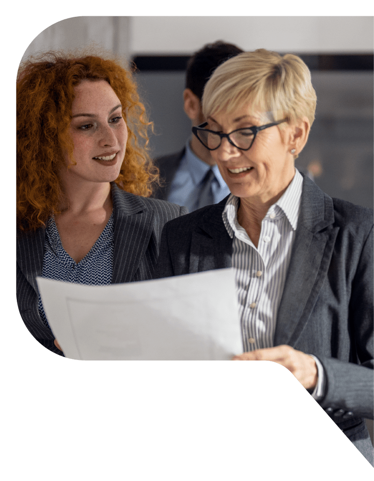 Two women in blazers looking at a document.